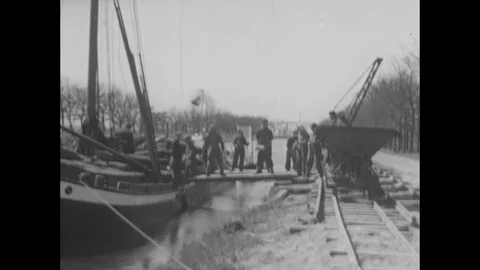 1940s-Workers unload brick from a boat into a group of train cars at Westerbork Stock Footage 86823485