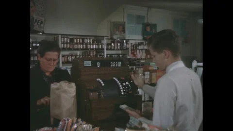 1940s: Young man totals an order in a cash register. Woman grabs her bag of Stock Footage 280053777
