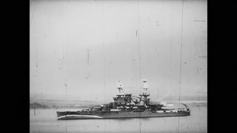1940s:Battleship sails in sea. Bombs explode on ship, ship goes up in flames. Stock Footage 218209930