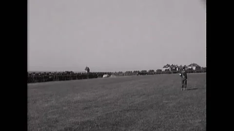 1945 - On May 30, while a military band plays, cars drive around a field, lined Stock Footage 217382426