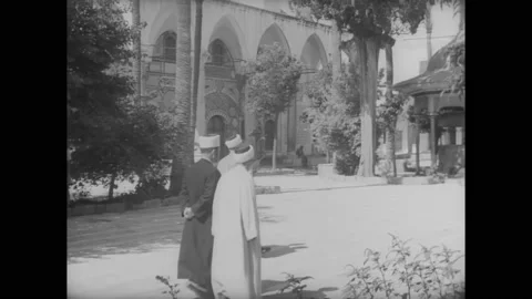1945 - Men pace by a mosque in Palestine, while others go to a bazaar. Stock Footage 234501609