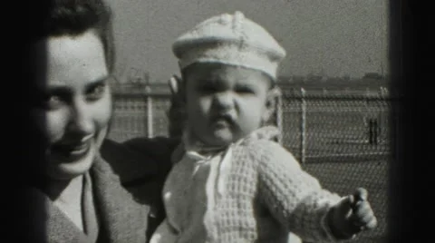 1946: baby in crocheted white outfit is held by mother Stock Footage