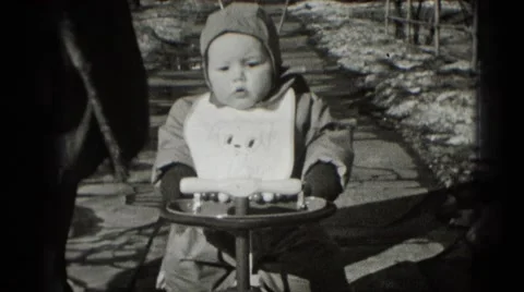 1947: babies first bike ride down snowy winter sidewalk street MIDDLETOWN Stock Footage