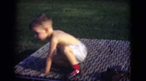 1947: baby toddler boy sitting on outdoor picnic blanket on hot summer day Stock Footage