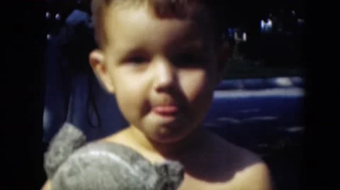 1947: boy holding teddy bear stares into camera while countryside golfer tees Stock Footage