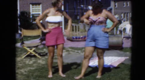 1947: women standing in summer with bathing suits and shorts on in yard Stock Footage