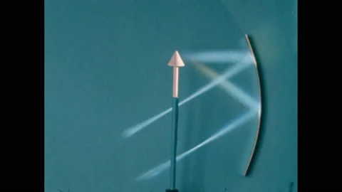 1950s: Arrow on a stand with two light beams reflecting from a concave mirror in Video stock 219633357