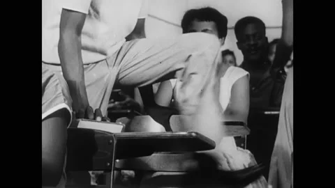 1950s: Black students sit in desks in crowded classroom. White students in desks Stock Footage