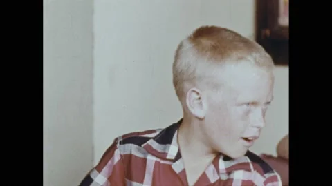 1950s: Boy in classroom talks to boy sitting next to him. They play with a Stock Footage 237700667