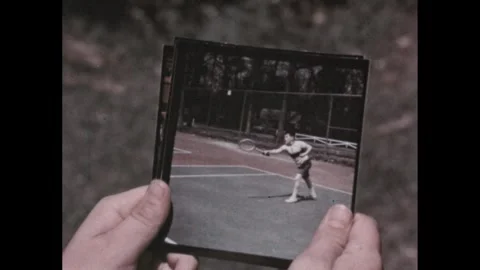 1950s: Boy flips through stack of photos outdoors. Postal worker knocks on door Stock Footage 295293109