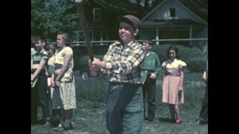 1950s: Boy hits baseball with bat and runs. Children watch boys play baseball in 動画素材 273883915