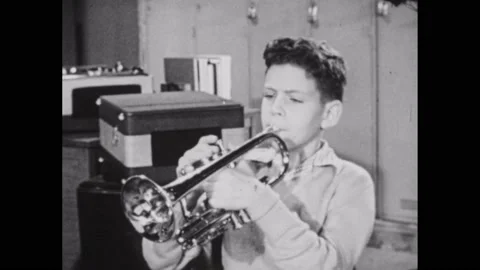 1950s: Boy plays tuba. Boy plays trumpet, improvising notes. Stock Footage