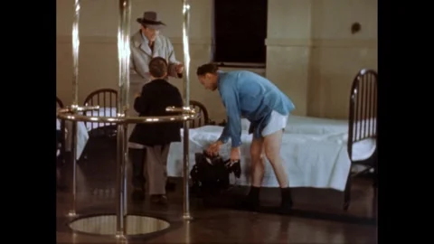 1950s: Boy in room of beds with two men. One man gets into a bed and pretends to Stock Footage 272975867