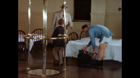 1950s: Boy in room of beds with two men. One man gets into a bed and pretends to Stock Footage 272975872