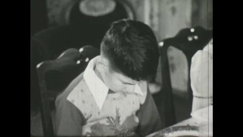 1950s: boy says grace at table. Boy drinks glass of milk and eats cookie. Stock Footage