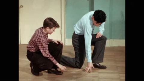 1950s: A boy stops walking and kneels to point.  Another boy stops further and Vídeos de archivo 167181814