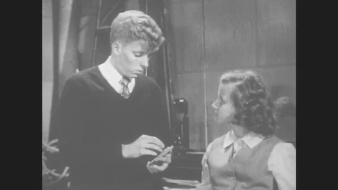 1950s: Boy Talking To Girl. Boy Picks Up Book. Man With Mustache Looks At Boy Stock Footage