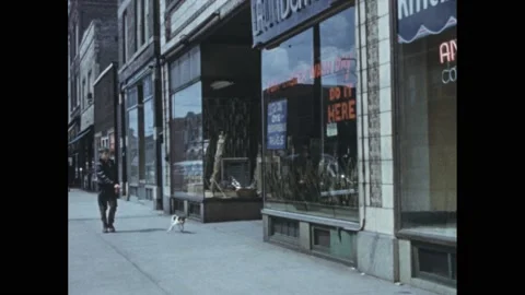 1950s: Boy walking down street with dog, stops to look in store window. Stock Footage 168630754