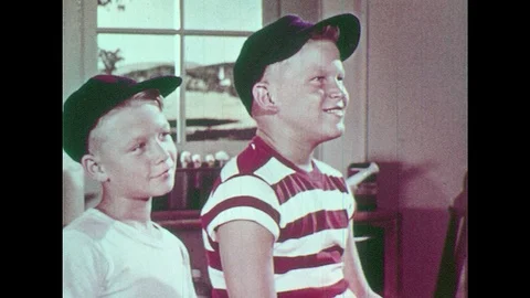1950s: Boys in hats sitting and looking. Man with apron talking, gesturing with Stock Footage