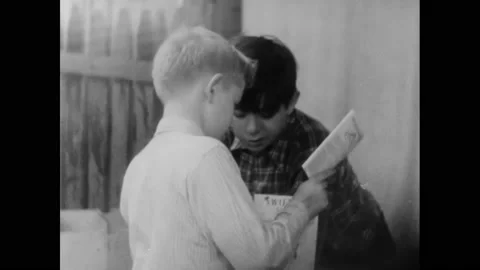 1950s: Boys looking at pamphlet, talking to each other. Boys setting type on 库存影片 163609161