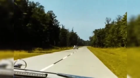 1950's Car Passing the Opposite Side on a Highway Through a Wooded Area Stock Footage 244879713