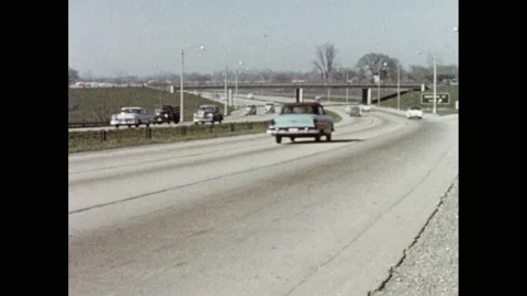 1950s: Cars driving on highway. View of steel mill. Tilt down to rail cars. Stock Footage