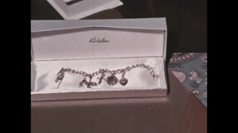 1950s: Charm bracelet sits in box on desk near catalog and dictionary. Stock Footage 295293204