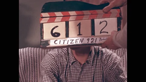 1950s: Citizen 921 clapper board in front of young actor’s face. Actor laughs on Stock Footage 219965449