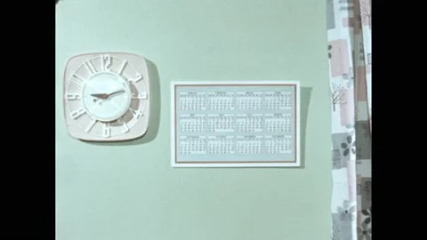 1950s: Clock and calendar on wall.  Night.  Men climb hill.  Man speaks and Stock Footage 165356672