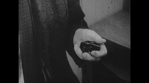 1950s: Close up, hand presses button. Man looks behind box. Food falls into Видео 126013691