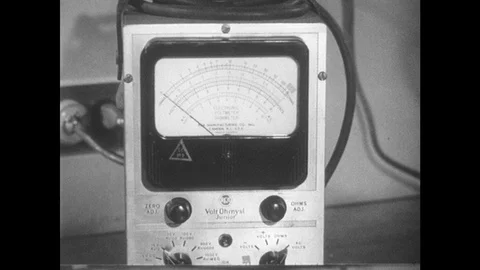1950s: Close up of voltmeter. Man with equipment in lab. Hand puts wire on Stock Footage 89858407