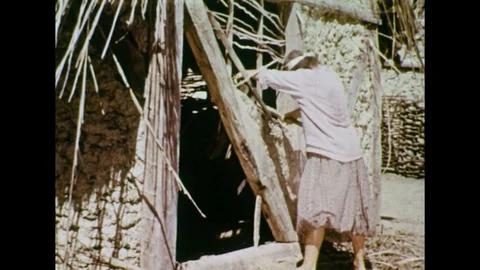 1950s: Colonist chops wood from side of house, colonial man approaches. Stock Footage