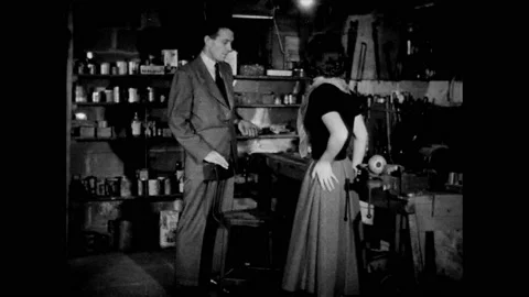 1950s: Couple talk in basement.  Man gestures to area under work bench. Stock Footage 160572693