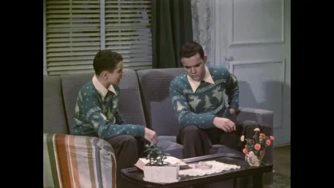 1950s: Dinner table in house. Boy sits on couch talking with older self. They Video stock 276327222