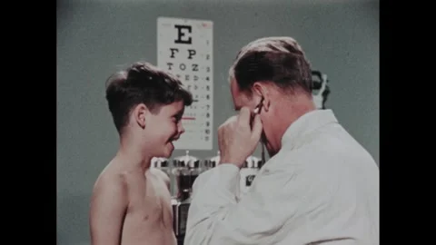 1950s: Doctor physically examines young boy. Boy laughs being tickled. Doctor 動画素材 284028400