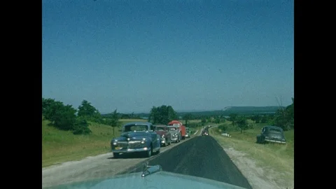 1950s: Driving past construction worker and line of cars facing opposite 動画素材 99671638