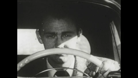 1950s: Drowsy driver closes eyes behind wheel of car. Driver's vision blurs. Stock Footage 126009588