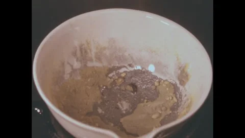 1950s: Elements in bowl over burner heat and burn, leaving charred residue. Stock Footage 272976711