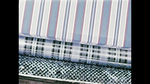 1950s: Fabric runs through printer. Water fall in machine. Woman guides fabric Stock Footage 104729950