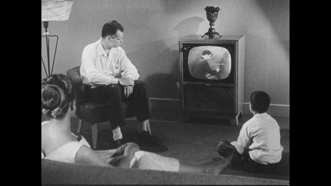 1950s: Family gathered around the TV set in  a living room. Hurricane special Stock Footage