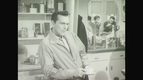 1950s: Father leans on counter in cafe, holds cup of coffee and thinks. Father Stock Footage