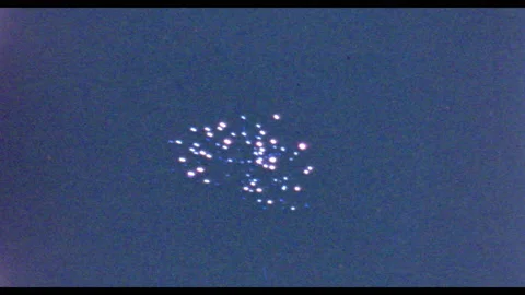 1950s: Fireworks explode in sky. Clouds of smoke rise from light in distance. 動画素材 132599831