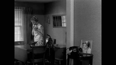 1950s: First Parish clock tower. Woman wipes a table. She squeezes past a vacuum Stock Footage 159005692