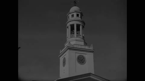 1950s: First Parish with clock tower. Cars parked along a tree lined street. Stock Footage 159005717
