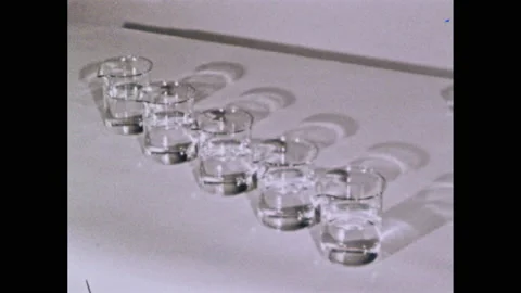 1950s: Five jars of liquid in row. Person sets down two dropper bottles and a Stock Footage 145208742