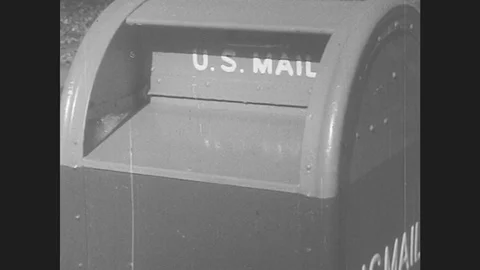 1950s: Flat packages are placed in U.S. Mail box. Mailman walks down sidewalk, Stock Footage 79978836