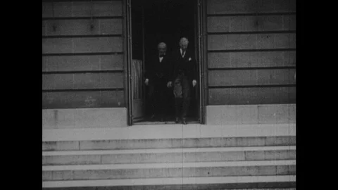 1950s: Four men exit building, stand at top of steps, talk, enter back into Vídeos de archivo 127730987