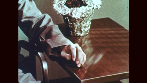 1950s: Glass breaks on floor. Hand hits table, tilt up to man with glasses. Stock Footage