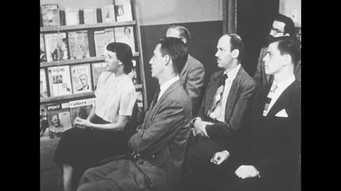 1950s: Group stands up and leaves the room, one man stays and sits alone. Stock Footage