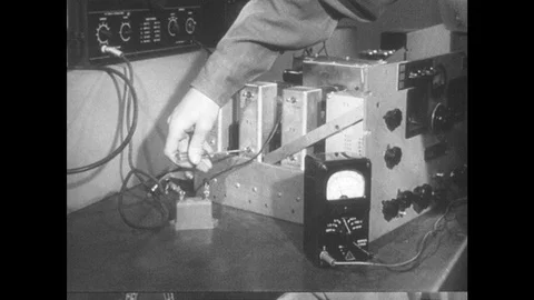 1950s: Hand adjusts screws on machine parts. Man in lab, flips over machine Stock Footage 89858368